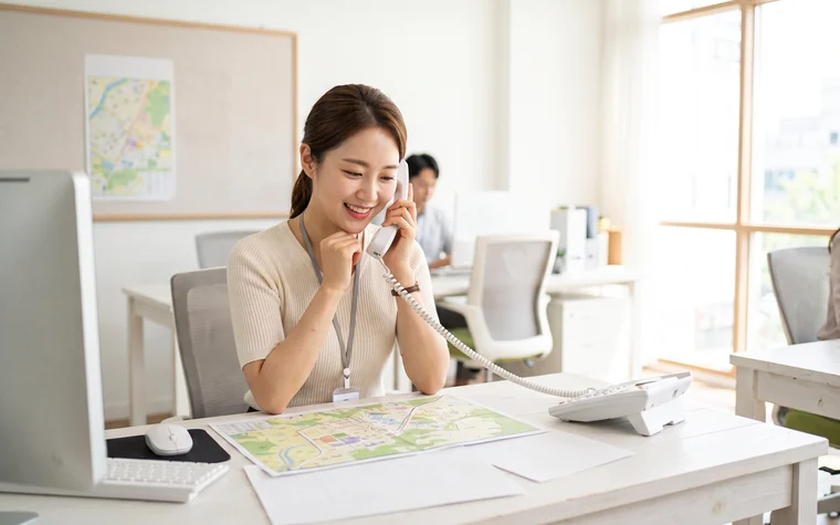 지도를 보며 유선전화로 매물 문의를 응대하는 공인중개사 – 부동산·중개 대표번호 활용